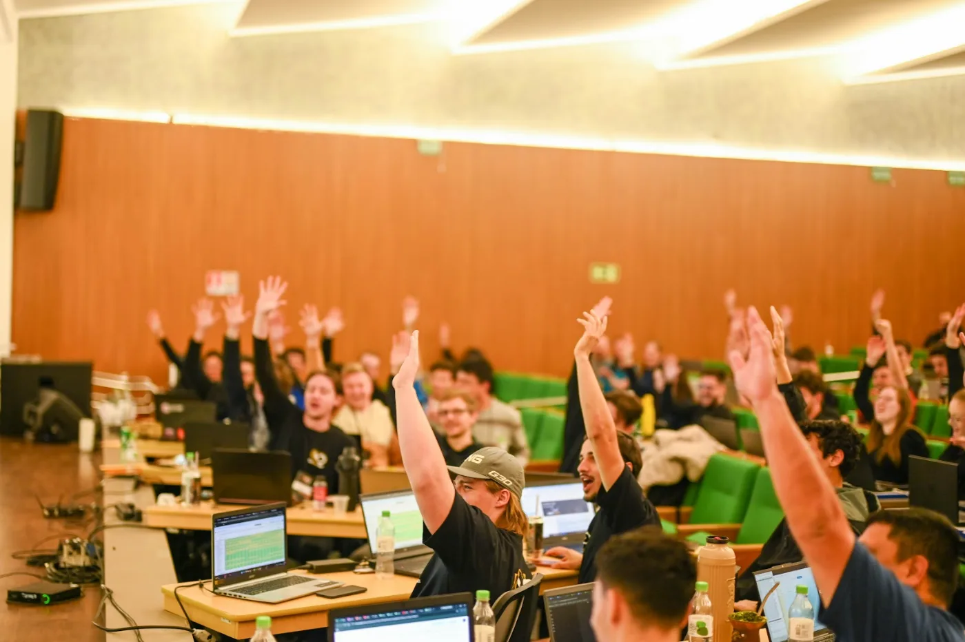 Students raising their hands in the auditorium during the class